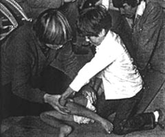 Ann Hallum teaches the older brother of a girl who is disabled by polio how to do stretching exercises.