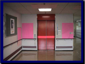 エレベーターの扉の写真、扉にピンク色の横線と両隣の壁がピンク色の布のようなものを貼り付けている
