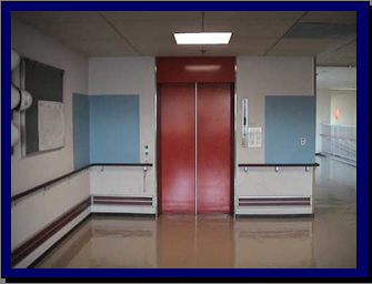 エレベーターの扉の写真、扉には何も貼っておらず、両隣の壁が水色の布のようなものを貼り付けている