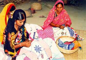 写真4：民族衣装姿の女性3人がパッチワークの手作業をしている様子。
