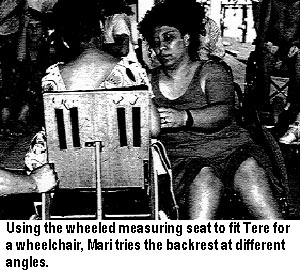 Using the wheeled measuring seat to fit Tere for a wheelchair, Mari tries the backrest at different angles.
