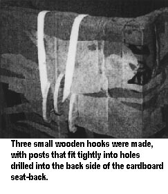 Three small wooden hooks were made, with posts that fit tightly into holes drilled into the back side of the cardboard seat-back.