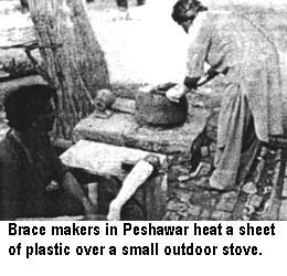 Brace makers in Peshawar heat a sheet of plastic over a small outdoor stove.