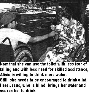 Now that she can use the toilet with less fear of falling and with less need for skilled assistance, Alicia is willing to drink more water. Still, she needs to be encouraged to drink a lot. Here Jesus, who is blind, brings her water and coaxes her to drink