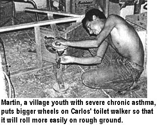 Martin, a village youth with severe chronic asthma, puts bigger wheels on Carlos' toilet walker so that it will roll more easily on rough ground.