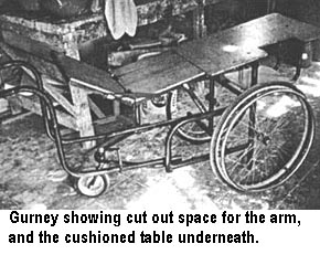 Gurney showing cut out space for the arm, and the cushioned table underneath.
