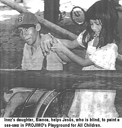 Inez's daughter, Bianca, helps Jesus, who is blind, to paint a see-saw in PROJIMO's Playground for All Children.