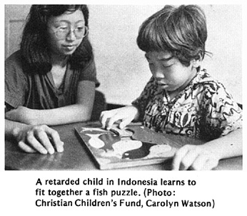 A retarded child learns to fit together a fish puzzle.
