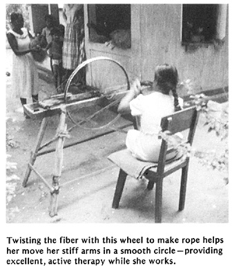 Twisting the fiber with this wheel to make rope helps her move her stiff arms in a smooth circle - providing excellent, active therapy while she works.