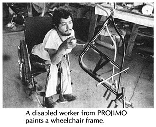 A disabled worker from PROJIMO paints a wheelchair frame.