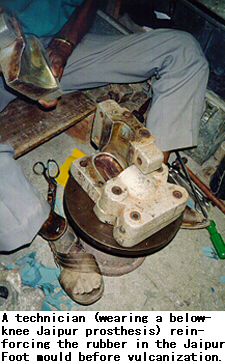 A technician (wearing a below-knee Jaipur prosthesis) reinforcing the rubber in the Jaipur Foot mould before vulcanization.