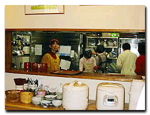 photos of a bustling kitchen with rice cookers in the foreground