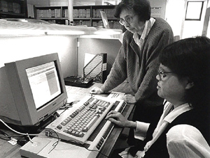 写真：利用者にコンピュータの使い方の指導をするスタッフ 