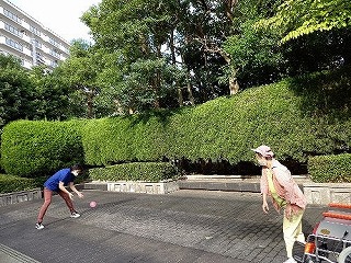 車いすから立ち上がってボール投げをしているマリさん