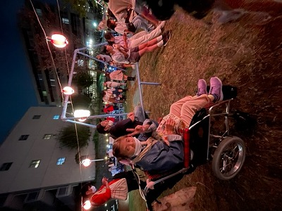 夜の秋祭りでマリさんが車いすでピースサイン