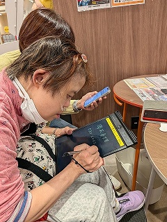 ドコモショップでタブレットに記入しているマリさん