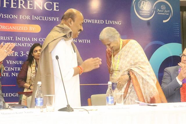 インド社会正義・エンパワーメント省大臣（左）に対し、笑顔で挨拶をする共催者代表のウマ・トゥリ博士（右）。