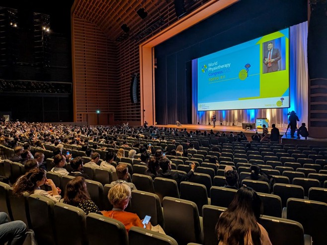 東京国際フォーラムで開催された世界理学療法連盟学会2025（WPC2025）開会式の様子。約5,000名が参加した大規模な会場のスクリーンには、登壇者の映像とともに「World Physiotherapy Congress 2025 TOKYO」のロゴが大きく映し出されている。