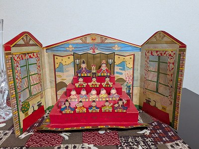 74年前の雑誌「小学１年生」の付録のお雛様。組み立てられた紙のひな壇に、お内裏様やお雛様などが4段に並んでいます。