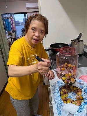 凍らせた梅をお玉ですくって、大きなガラス瓶に入れている真理さん