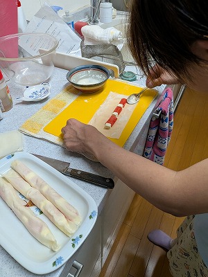 春巻きの皮に、カニカマとチーズをのせて巻いて作っている様子